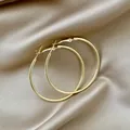 Vue détaillée montrant la finition polie de grandes créoles dorées sur du tissu en satin - Grande Créole Minimaliste Or (E3180-1)