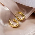 Vue rapprochée détaillée de boucles d'oreilles créoles dorées sur fond de soie champagne luxe. - Créole Epaisse Or (E2564)