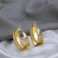 Gros plan de boucles d'oreilles créoles dorées irrégulières avec fini texturé - Texture Brossée Or (E3419-1)