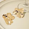 Détail macro d'élégantes boucles d'oreilles fleur en métal doré froissé irrégulier - Fleur Plissée Or (E4473)