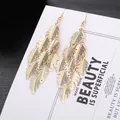 Boucles d'oreilles pendantes plumes dorées superposées avec finition métal texturé - Style Plume Multi-couches Or (E1496-1)