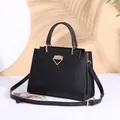 Dettaglio di una borsa a mano in pelle nera strutturata con chiusura a triangolo dorata - Nero / Lunghezza Della Base 28 Cm Altezza 21 Cm Larghezza 9 Cm