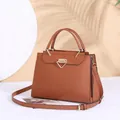 Vista laterale dettagliata dell'elegante borsa in pelle marrone con dettagli dorati - Marrone / Lunghezza Della Base 28 Cm Altezza 21 Cm Larghezza 9 Cm