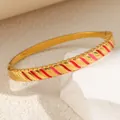 Detail eines Armbands aus Titanstahl mit rot-rosa Emaille-Streifen auf Gold. - Sz108 - Goldfarbenes Öltropfen-armband
