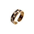 Primo piano di un anello aperto in acciaio dorato con motivi geometrici in smalto bianco e nero - Geometrico Bianco e Nero Oro (R2595-29)