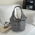 Minimalistische schwarz-weiß karierte Nylon-Canvas-Tasche auf einem weißen bequemen Sofa. - Schwarz