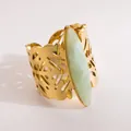 Dettaglio anello largo in acciaio dorato con pietra verde e design a foglia traforata. - Stile Pietra Verde Chiaro Marquise / verde chiaro