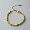 Close-up detail of a gold braided stainless steel wheat chain bracelet with lobster clasp. - Braided Wheat Chain (ne276) / Gold
