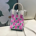 Detailed view of cream knitted mini tote bag with pink tulip pattern and metal button - Silicone Phone Case #6