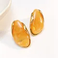 Elegant irregular orange resin stud earrings with sophisticated gold-toned metal trim - Ginger Yellow