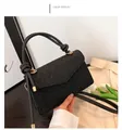 Close-up detail of a minimalist black retro square bag with woven texture and knotted handle - Black