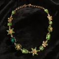 Detalle del collar vintage de flores con gemas verdes sobre terciopelo negro suave. - Verde