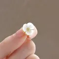Primo piano di un'elegante spilla a fiore con petali in madreperla e finitura oro - Piccolo Fiore Con Spilli Multipli
