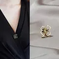 Detail view of a golden four-leaf clover safety pin on elegant grey satin fabric. - Hollow Four-Leaf Clover Pin