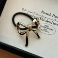 Close-up of elegant gold bow alloy hair tie with black elastic band texture detail. - Gold Bowknot