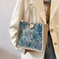 Primer plano de un bolso tote jacquard floral con asas de cuerda y botón de madera - Azul