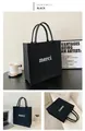 Detailed view of black felt tote bag with white merci print and minimalist design - 23*23*13cm / Black