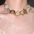 Detailed macro shot of a vintage gold necklace featuring elegant floral charms and pearls - Gold Flower Necklace