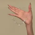Elegant silver clavicle chain with zircon and pearl drop charms held in hand SKU view - Silver