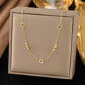 Elegant golden titanium steel necklace with clover charms presented on a grey jewelry box - Gold Bead Hollow Clover (H1196)