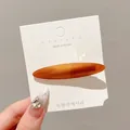 Elegant amber oval duckbill hair clip presented on a minimalist Korean style display card - Caramel color