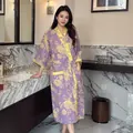 Elegant purple floral cotton gauze bathrobe with yellow trim in bathroom setting. - Tranquil Floral Purple Yellow