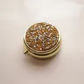 Macro detail view of a circular gold metal pill box with sparkling rhinestone inlay - Gold - Silver Lemon Yellow Rhinestone