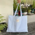 Nahaufnahme einer blau-weiß gestreiften Canvas-Einkaufstasche mit dekorativem Aufnäher - Blau