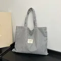 Black and white vertical striped canvas tote bag with a minimalist front heart label - Black