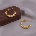 Detailansicht goldener gedrehter Creolen mit filigranem Design auf seidigem Hintergrund. - Gepunktete Textur Hohl C-Form Ohr-Schnalle (E-074-Gold)