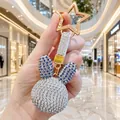 Detailansicht eines luxuriösen, mit Strass besetzten Hasenkopf-Schlüsselanhängers in der Hand. - Lila Ohren Kaninchenkopf