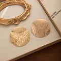 Gros plan de boucles d'oreilles dorées texturées vintage dans un coffret cadeau. - Doré