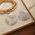 Gros plan de boucles d'oreilles rondes argentées avec texture ondulée en relief - Argenté