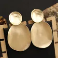 Gros plan de boucles d'oreilles géométriques dorées mates sur un présentoir - TLE97 Or / Doré