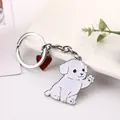 Close-up detail of a cute white cartoon waving dog keychain with a red heart charm - Bichon Frise / Poodle / 10cm