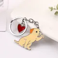 Close-up of a cute waving dog keychain with a red heart charm and zinc alloy finish - Golden Retriever / 10cm