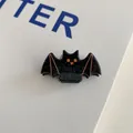 Close-up of a black acrylic bat hair clip with orange eyes and silver glitter details - Orange Bat Clip