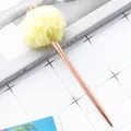 Rose gold ballpoint pen with yellow pom-pom and crown topper on a grid background - Crown Yellow Pompom