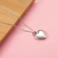 Close-up view of a silver heart-shaped locket necklace featuring a pink birthstone. - Light Pink