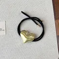 Vista detallada de una goma de pelo negra con un dije de corazón de aleación dorada. - Dorado (1#Gold)