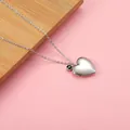Detail view of heart-shaped locket necklace with green birthstone gem. - Dark Green
