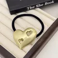 Detailed macro view of golden brushed metal heart ornament on a black hair tie. - Double Hollow Heart - Gold (13#Double-Hollow-Heart-Gold)