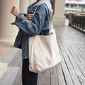 Vista laterale dettagliata di una tote bag minimalista in tela crema - Bianco Sporco