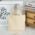 Detail view of a minimalist cream canvas tote bag in a stylish lifestyle setting. - 8oz Open Style / Beige Apricot