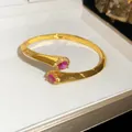 Elegante bracciale rigido aperto dorato con zirconi rosa a goccia e micro-pavé decorativo - Oro con zirconia rossa