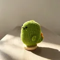 Handmade green crochet dinosaur toy for emotional support on a wooden stand - Dinosaur Green
