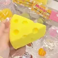 Detail view of a soft yellow cheese-shaped squishy toy being held for stress relief - Triangle Cheese Squeeze Toy