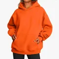 Detail showing the soft texture and kangaroo pocket of this oversized orange hoodie. - Orange