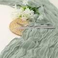Detail eines salbeigrünen Boho-Tischläufers aus Gaze mit Faltenoptik für Hochzeiten - 90*180cm / Hellgrün