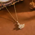 Elegante collana con ciondolo a cigno dorato con zirconi incastonati su sfondo di sabbia - Collana T064 Cigno D'oro